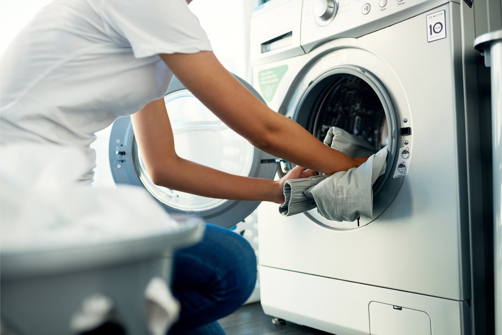 femme mettant des vêtements dans une laveuse de buanderie